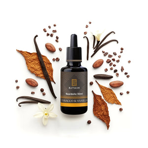 Rithim tobacco and vanilla Beard Oil bottle surrounded by vanilla beans, cocoa beans, and dried leaves on a white background